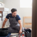Man doing DIY plumbing at home