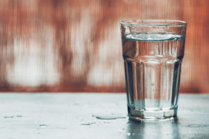 Water glass with spill against hazy brown background