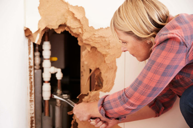 Woman repairing burst pipe with wrench