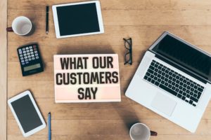 ‘What our customers say’ message on table with laptop and calculator