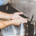 Man washing hands under sink faucet