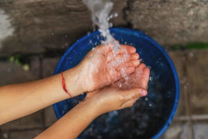 Water flowing into the hands of a child over a bucket