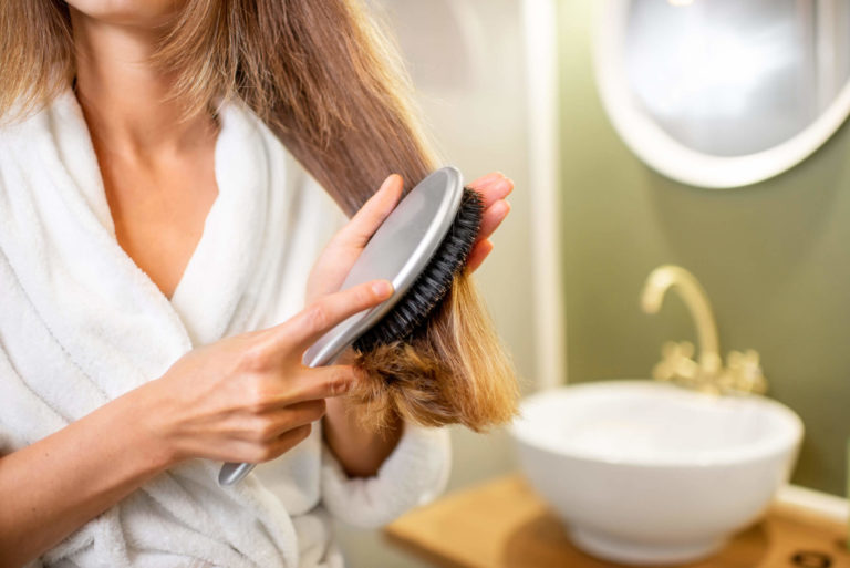 Woman in housecoat combing hair in bathroom